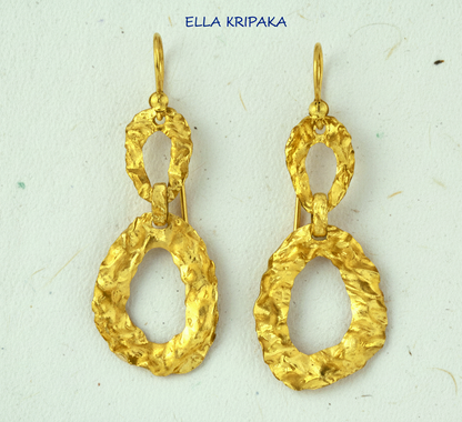 Organic hammered uneven 24k 9999 Gold earrings on a grey surface, and with 'ELLA KRIPAKA' branding
