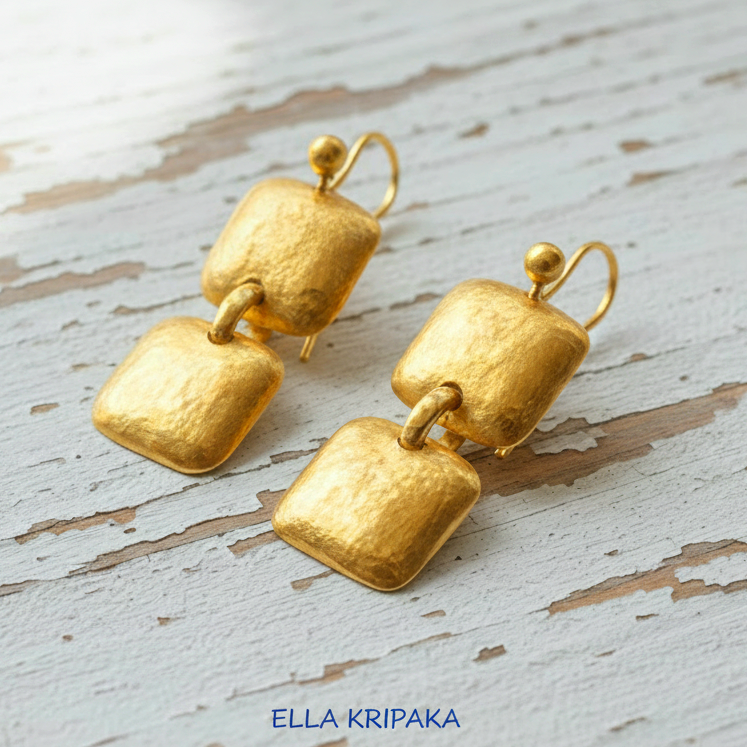 Hammered 24k gold, pure 9999 gold convex square earrings with shiny forged gold textures on white old wooden surface, artist-jeweler 'Ella Kripaka' branding