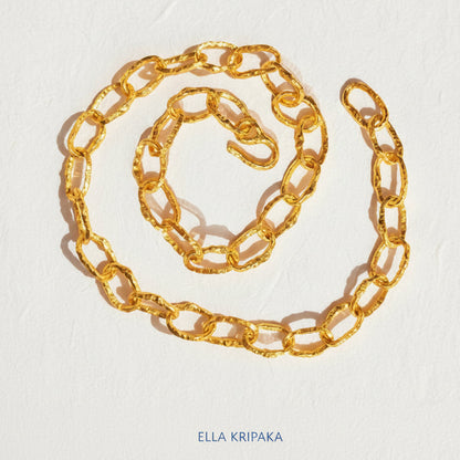 Organic 24k Gold hammered uneven textured chain necklace with thick hook clasp on a white craft paper surface, with artist 'Ella Kripaka' branding