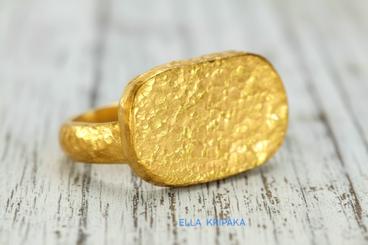 Hammered twisted 24k Gold 9999 gold signet thick ring Ancient Rome style with textured gold on white old wooden background, branded 'Ella Kripaka'