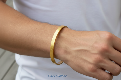 Hammered 24k 9999 gold bangle thick bracelet Ancient Rome style worn by a woman on hand and on a white t-shirt background, artist-jeweler name 'Ella Kripaka' branding