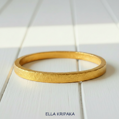 Hammered 24k 9999 gold bangle thick bracelet Ancient Rome style on a white wooden background, artist-jeweler name 'Ella Kripaka' branding
