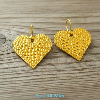 Organic 24k 9999 gold hammered hearts earrings with shiny gold textures are on old wooden background, artist-jeweler's name 'Ella Kripaka'