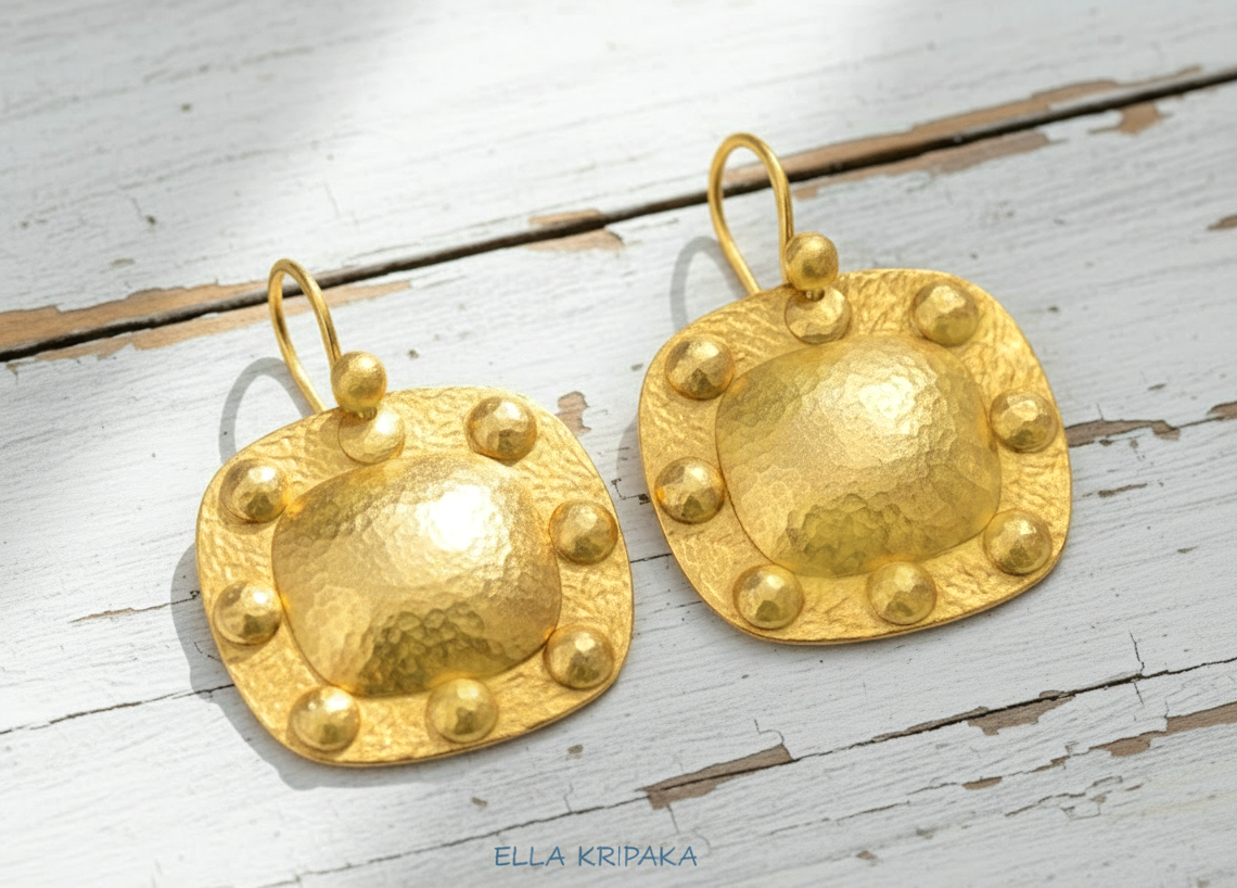 Solid 24k 9999 gold hammered Byzantine convex square earrings with hook clasps and shiny forged gold textures on old wooden background , artist's name 'ELLA KRIPAKA'