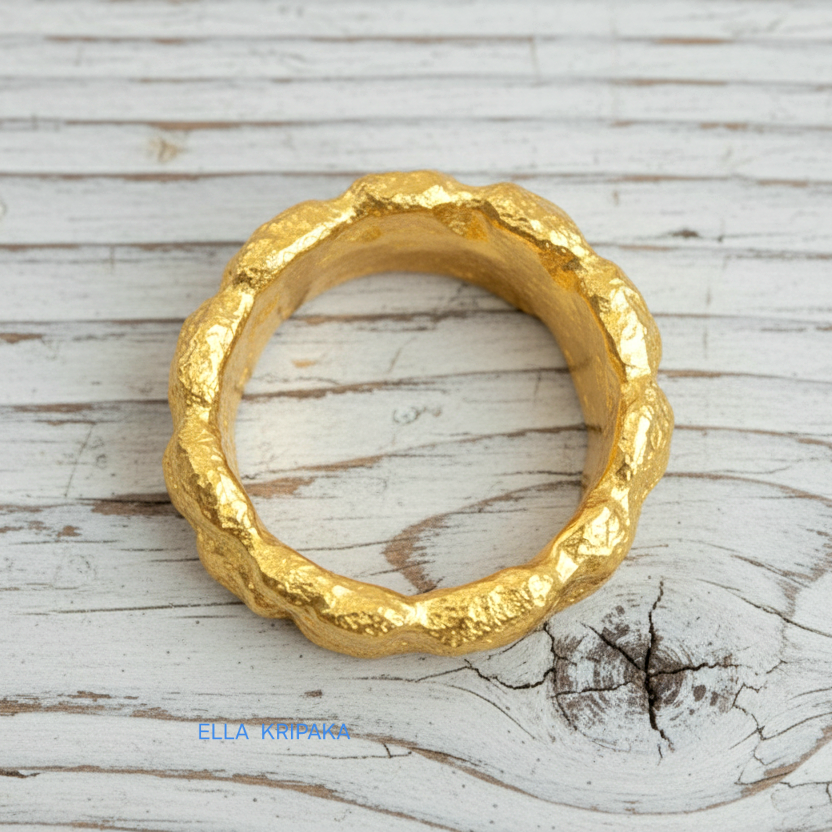Organic hammered 24k 9999 Gold ring signet with uneven wavy thick edges on white old wooden surface, artist-jeweler's name 'Ella Kripaka' is written in picture