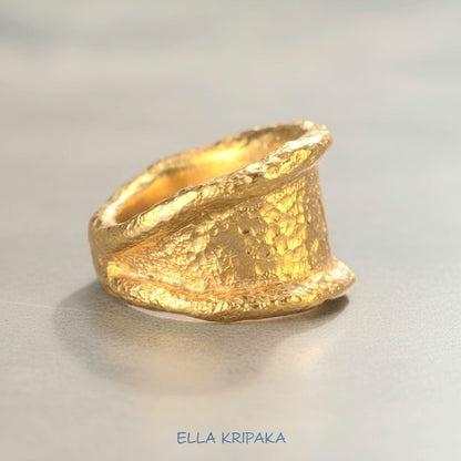 Organic hammered 24k 9999 gold ring signet with uneven thick edges on grey surface, artist-jeweler's name 'Ella Kripaka' is written in picture