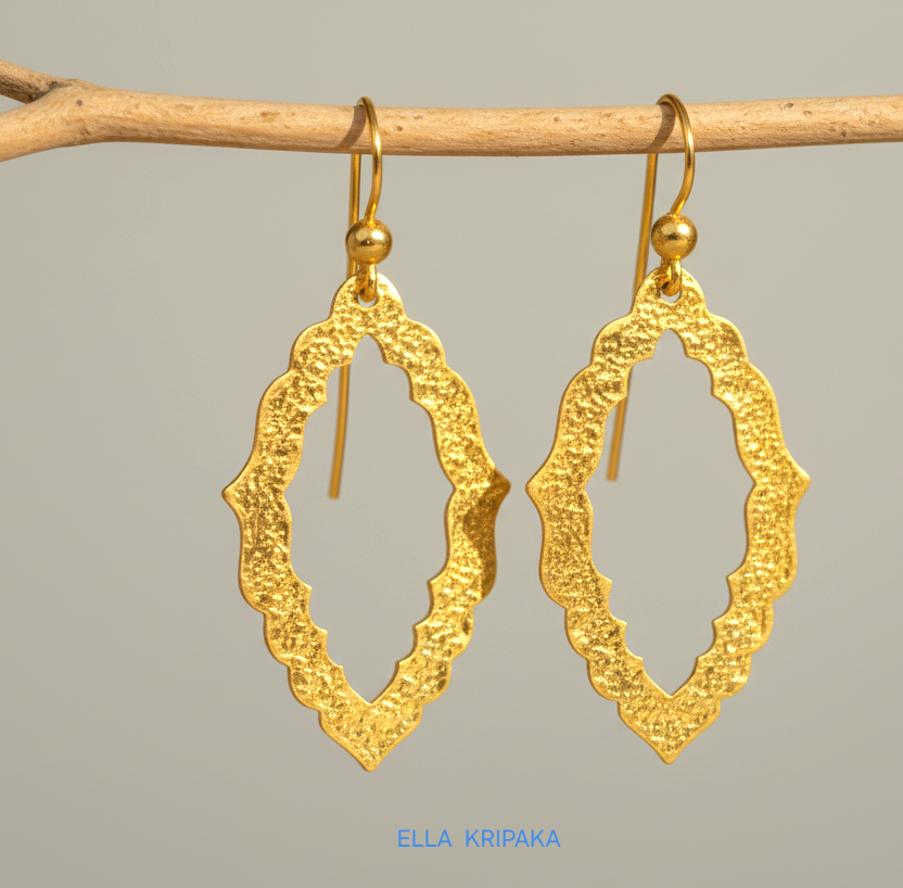 24k 9999 gold hammered Byzantine baroque convex earrings with shiny gold textures are hanging on branch on grey background, artist-jeweler's name 'Ella Kripaka'