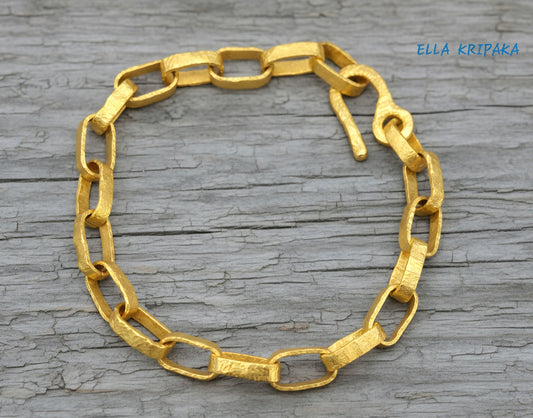 Hammered 24k 9999 gold chain thick bracelet with thick hook clasp Ancient Rome style on a old wooden background, artist-jeweler name 'Ella Kripaka' branding