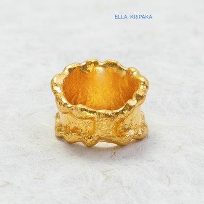 Organic hammered 24k 9999 Gold ring signet with uneven wavy thick edges on white old wooden surface, artist-jeweler's name 'Ella Kripaka' is written in picture