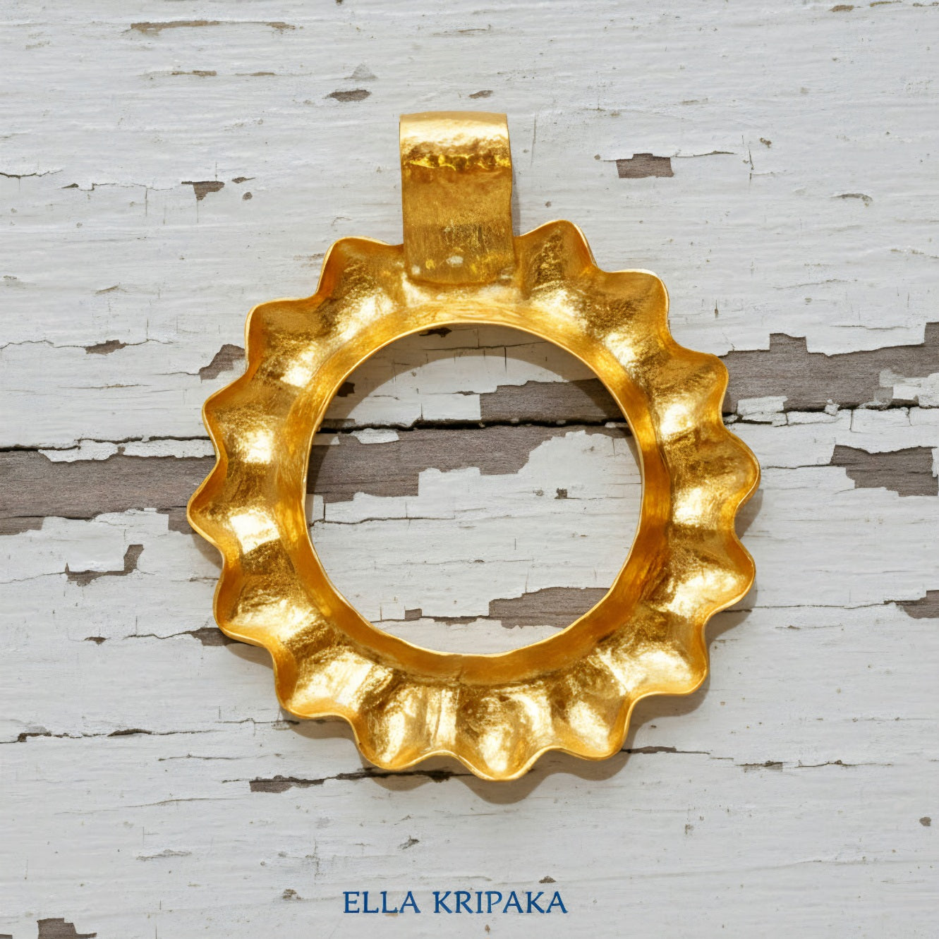 24k 9999 gold hammered convex Sun pendant on a white old wooden surface, branded 'Ella Kripaka'