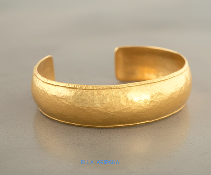 24k 9999 gold hammered Ancient Rome convex  cuff bracelet on a grey concrete surface, branded 'Ella Kripaka'