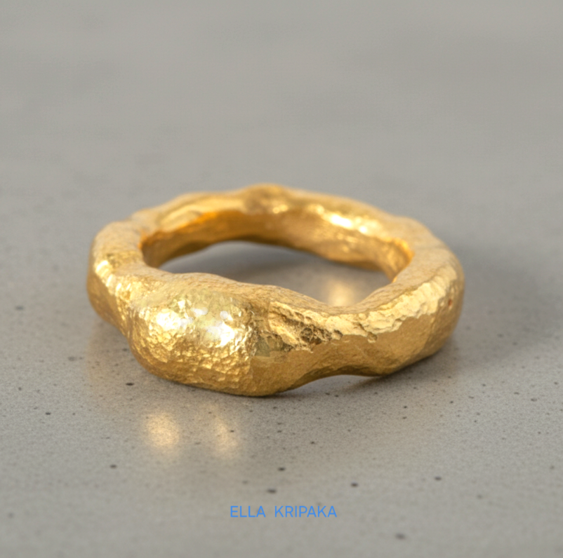 organic hammered 24k Gold thick uneven ring signet with a textured design on a grey concrete background, branded 'Ella Kripaka'