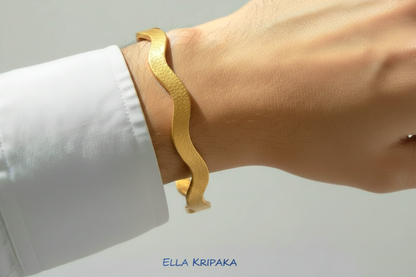 24k gold hammered bracelet textured bangle with wavy design is wearing on man's hand with white shirt and on neutral light background, branded 'Ella Kripaka'