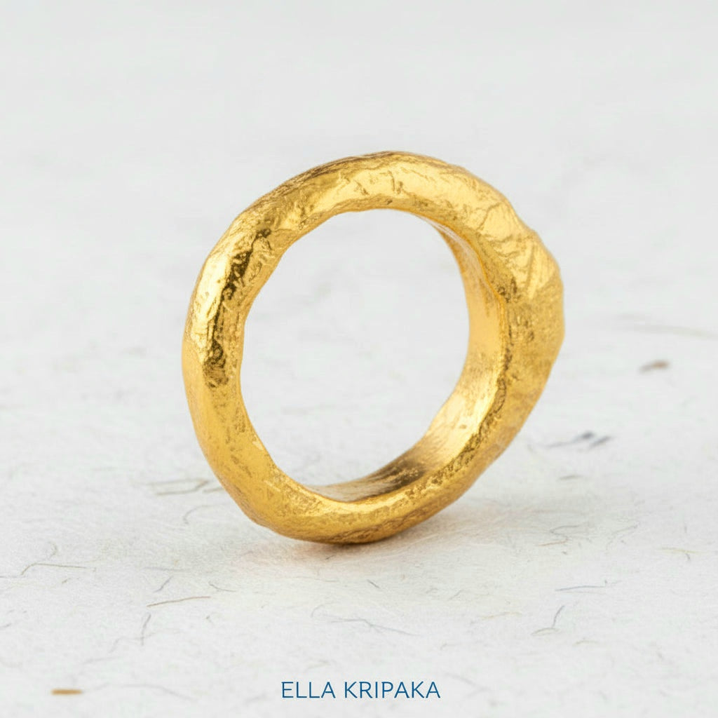Organic hammered 24k 9999 Gold ring thick signet with uneven edges on white paper surface, artist-jeweler's name 'Ella Kripaka' is written in picture