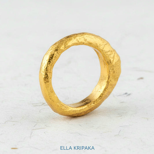 Organic hammered 24k 9999 Gold ring thick signet with uneven edges on white paper surface, artist-jeweler's name 'Ella Kripaka' is written in picture