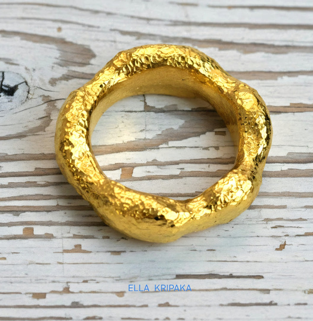 Hammered 24k 9999 Gold thick uneven wavy ring organic with textured gold on a white old wooden background, branded 'Ella Kripaka'