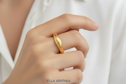 Hammered 24k 9999 Gold thick ring organic signet with a textured gold surface worn on woman's finger and on a blurred background, branded 'Ella Kripaka'